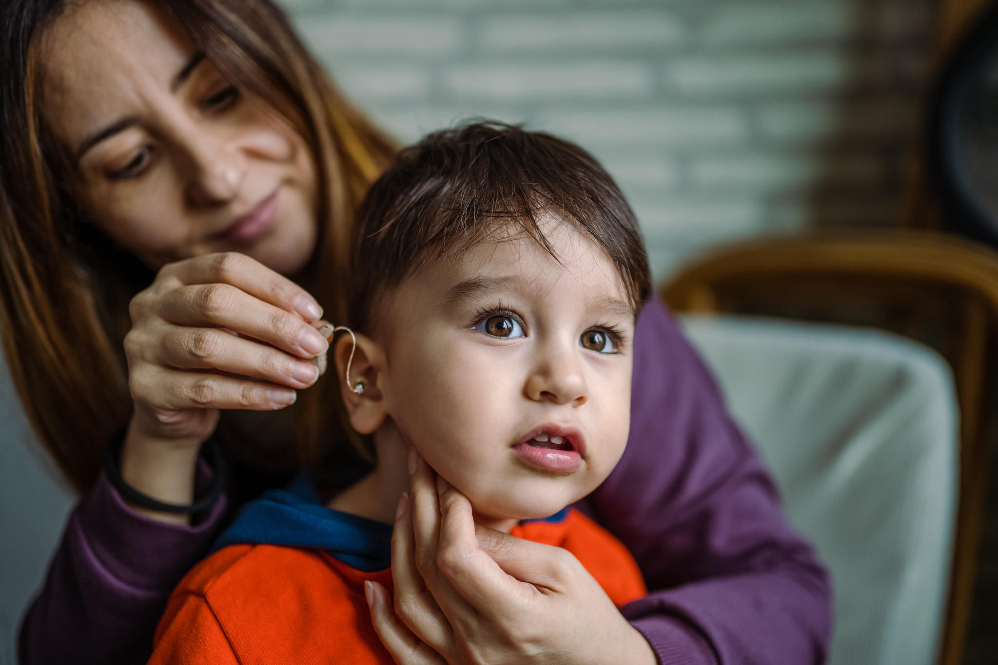 adult helping young student with hearing aid